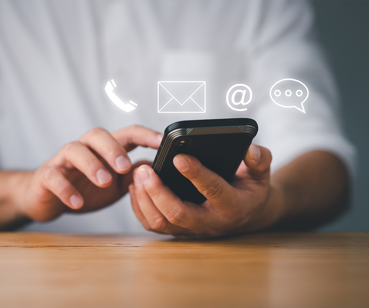 The image shows a person s hand holding a smartphone with various icons on the screen, including an envelope symbolizing email, a speech bubble indicating messaging, and a phone icon representing a call function.
